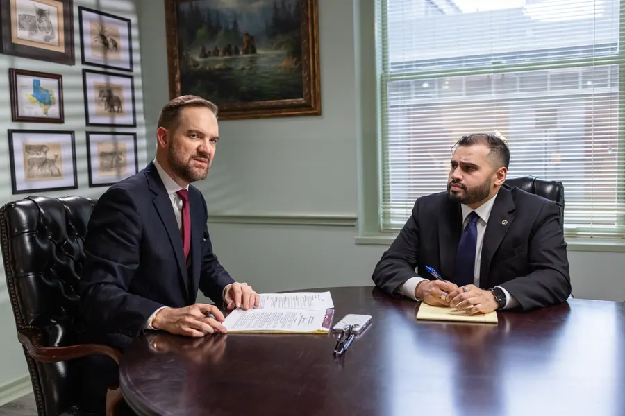An attorney and a client going through paperwork at a conference table in a Houston office